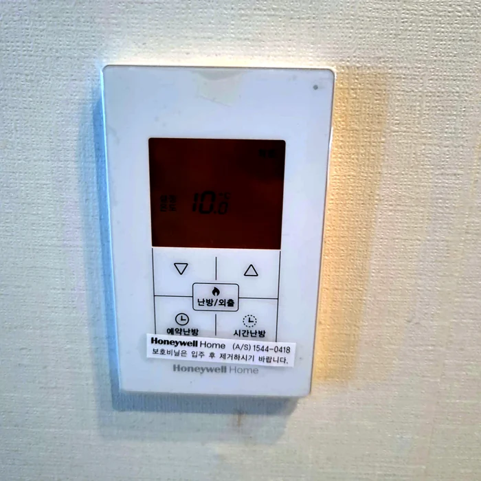 흰색 벽면에 설치된 디지털 난방 온도조절기 설정온도 화면